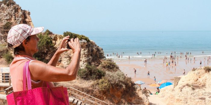 mulher a tirar fotografia ao areal da Praia dos três irmãos em Portimão